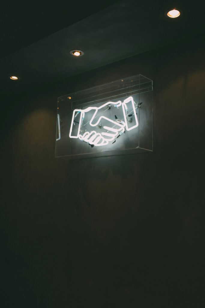 a image of a neon sign of two hands shaking. Why is PR consistency important