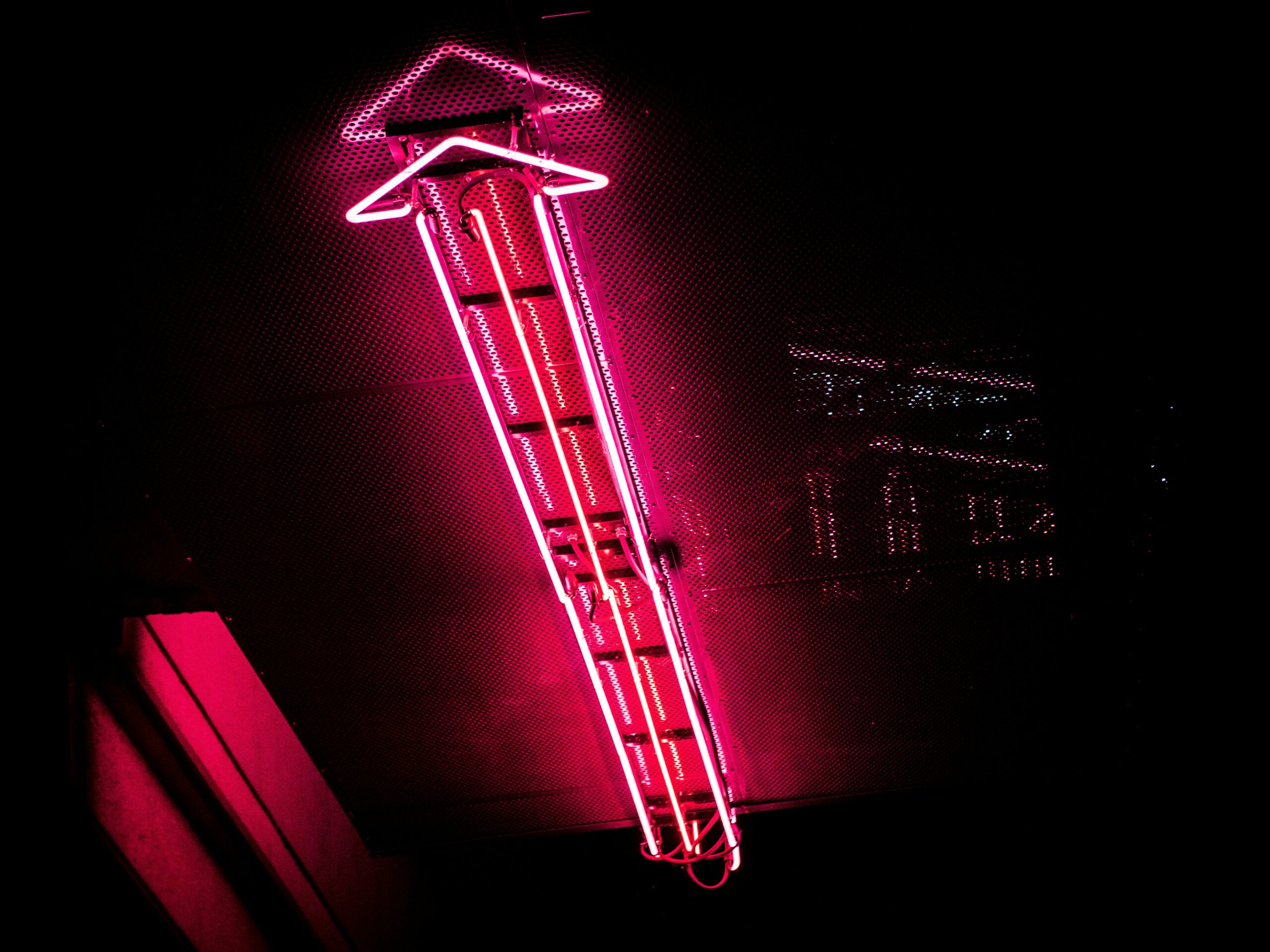 Our Service, Guaranteed Publishing. An image showing a pink neon arrow pointing up on a dark background